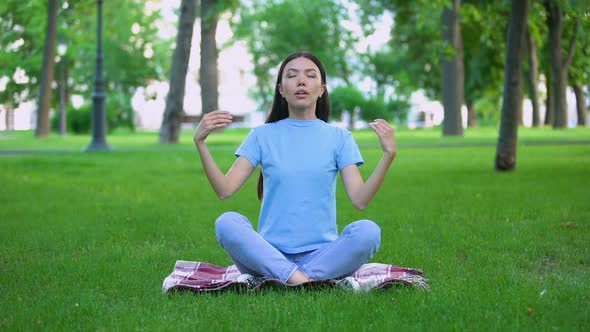 Attractive Young Lady Meditating in Park Sitting Lotus Pose, Relaxing Outdoors alt