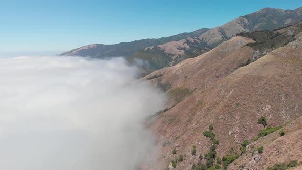 Drone flies above clouds towards mountains in Big Sur California