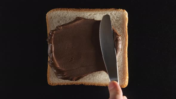 Human hand spreads a chocolate paste on a bread