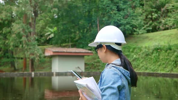 Female ecologist in safety hat working and controlling a quality of water alt