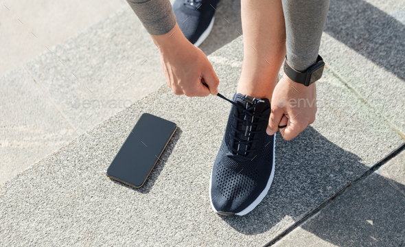 Healthy lifestyle, sport and exercise. Guy with fitness tracker tie laces on sneakers, telephone on
