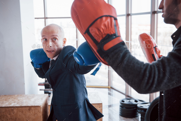 An angry bald businessman beats a boxing pear in the gym. concept of anger management