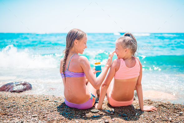 UV protection. Sister puts sunscreen on her little sister\'s nose