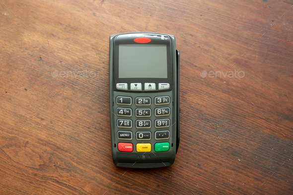 Payment machine, POS terminal on wooden background.