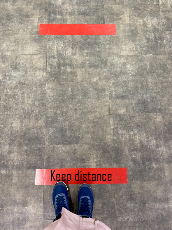 Person standing on tiled floor with a red line. Concept of keep distance, social distancing
