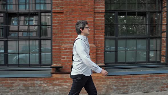 Middle Profile Shot of Man in Eyeglasses and Blue Shirt Walking Along the Street