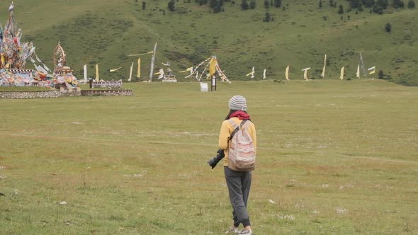 Female tourist with photo camera walking near flags and admiring landscape alt