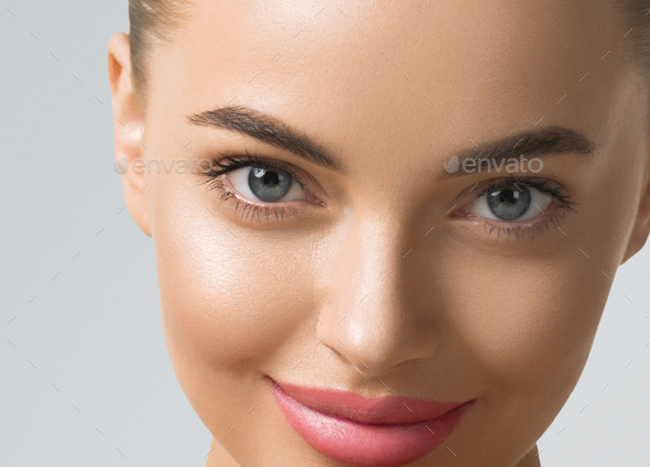 Clean skin woman face close up skin beauty tanned face beautiful smile over blue background
