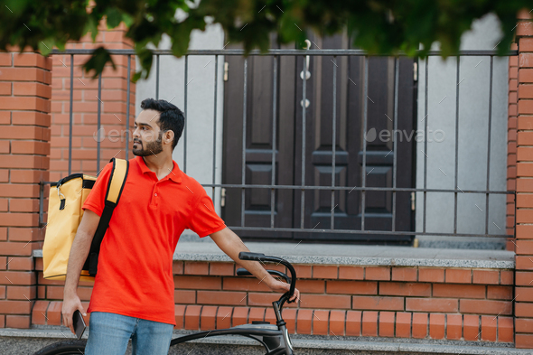 Courier with bicycle, delivery food service at home. Man with mobile phone finds address in city