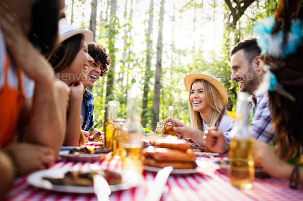 Group of happy friends eating and toasting at garden barbecue