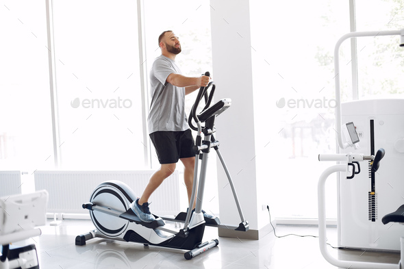 Bearded man using spin bike in physiotherapy room