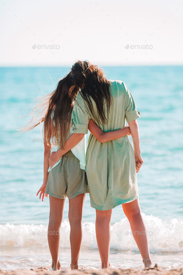 Beautiful mother and daughter on the beach enjoying summer vacation