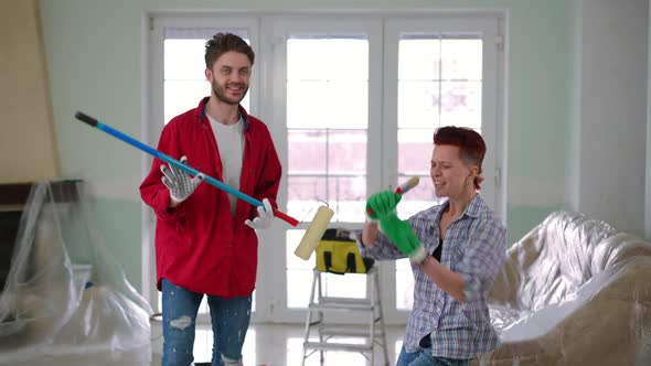 Joyful Carefree Couple Having Fun Painting New House Living Room Indoors alt