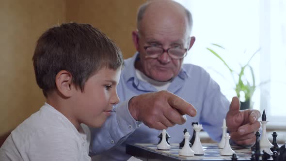 Game of Chess, a Cute Intelligent Male Child, Together with an Elderly Man in Glasses for Sight alt