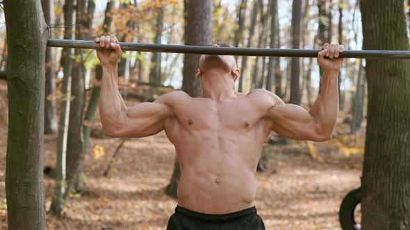 Strong Naked Guy Pulls Up On Pole. Exercise Emphasizes All The Muscles Of The Man. alt
