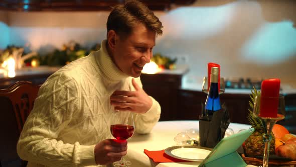 Side View Happy Man Waving at Tablet Video Chat Talking Sitting at Table with Red Wine alt