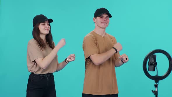 Young Couple are Synchronously Dancing to the Music on a Blue Background While Shooting a Video on alt