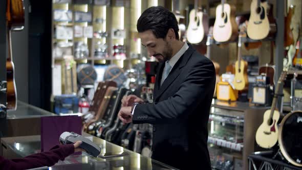 Young handsome man using smartwatch to express pay on counter  alt