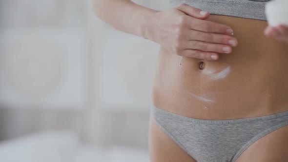 Woman Applying Moisturizer Cream on Her Belly alt