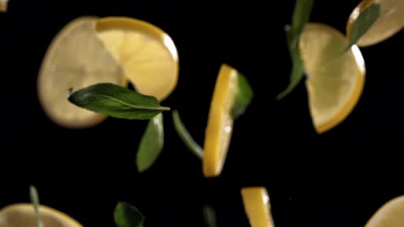 Slow Motion Shot of Flying Mint Leaves and Lemon Slices Collision in the Air alt