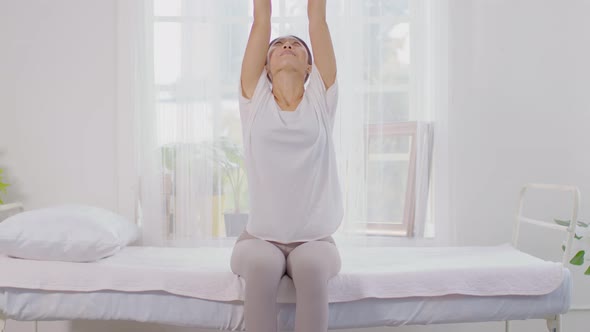 Calm of wellness Asian young woman sit on bed breathing and stretching before do yoga alt