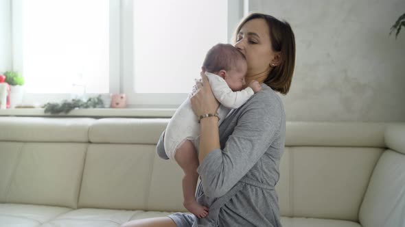 Happy Young Mother Holding Her Newborn Baby in Her Arms alt