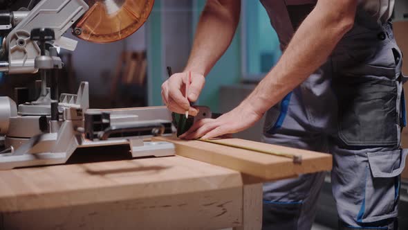 A Builder Measures a Wooden Board to Cut It on a Table Circular Saw