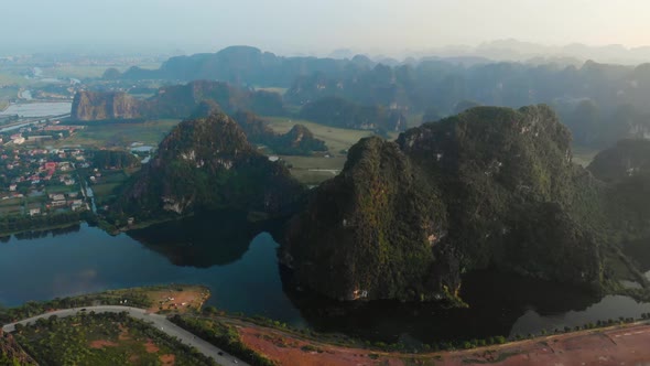 Aerial: North Vietnam karst landscape at sunset, drone view of Ninh Binh region, tourist destination alt