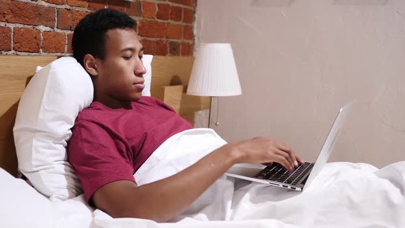 Angry Frustrated African Man Working Online at Night in Bed alt