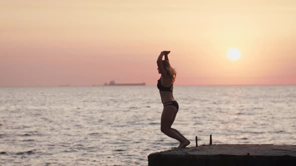 Young Youman Jumping From Sea Pier and Doing Frontflip During Beautiful Sunrise Slow Motion alt