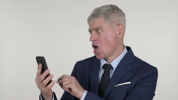 Shocked Senior Businessman Reacting To Loss on Smartphone, White Background alt