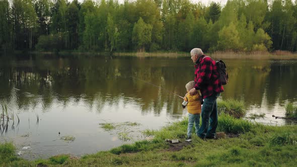 Weeknd in Nature Hike to Beautiful Forest Lake Grandfather and Grandson are Fishing alt