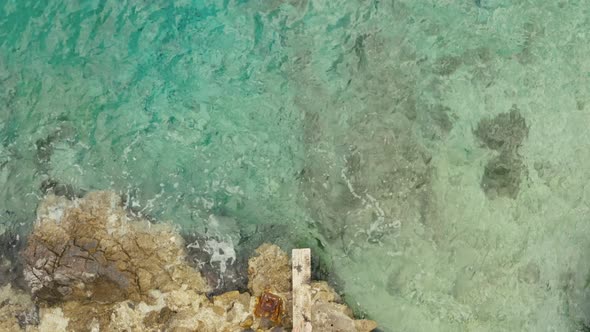 Top View Aerial Guy Jumps From a Pier Into the Sea Water alt