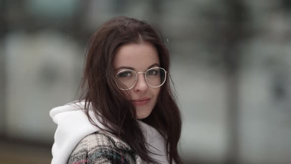 Portrait of a Beautiful Young Darkhaired Woman Without a Hat Wearing Round Glasses and a Plaid Coat alt
