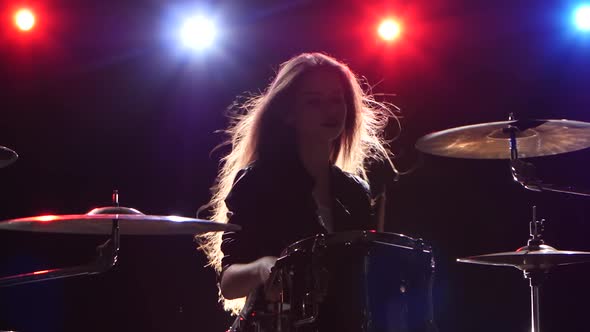 Girl Is Playing the Drums. Black Background. Red Blue Light From Behind alt