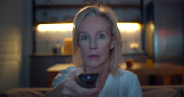 Aged Lady Watching Tv in Living Room Sitting on Sofa Holding Remote Control Changing Tv Channels alt