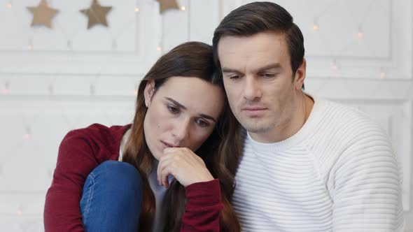 Portrait of Thinking Couple Sitting in Living Room alt