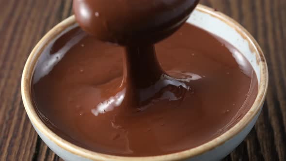 melted chocolate pouring into bowl from spoon, slow motion 