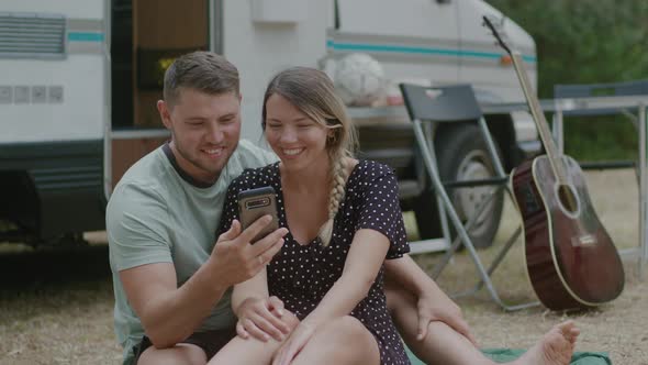 Young family couple talking video calling against motor home RV campervan alt
