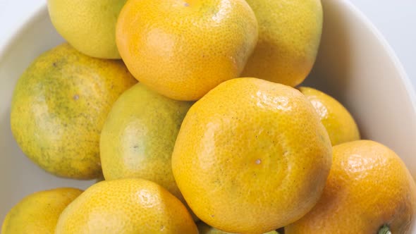 Fresh tangerines on white plate rotating in front of camera against the white background alt
