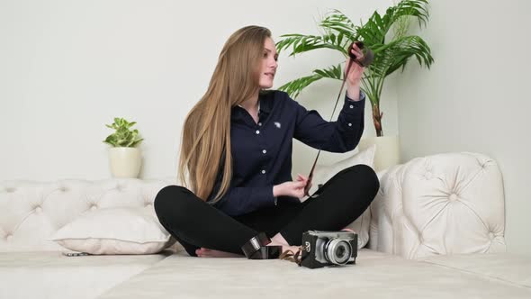 Female Photographer with Photographic Films and Vintage Film Camera Looking at Photographic Film alt