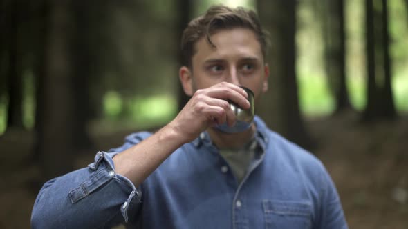 Hiker drinking coffee in the forest alt
