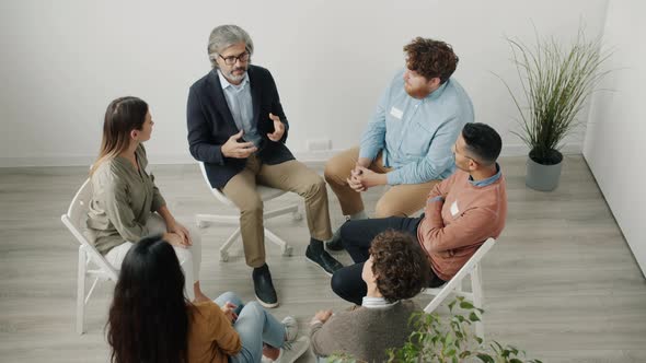 Professional Psychologist Speaking at Group Therapy Gathering Giving Advice to Troubled Patients alt