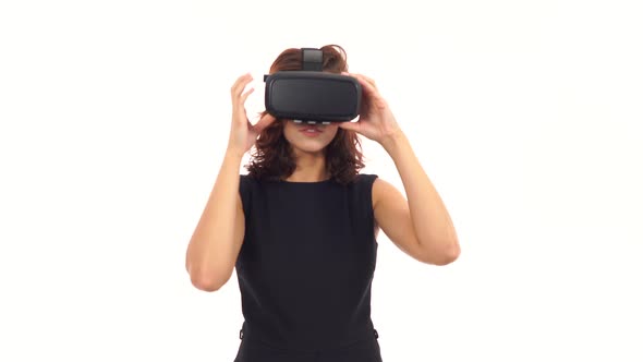 Attractive Young Woman in Black Dress Taking on and Wearing Virtual Reality Glasses Isolated Over alt