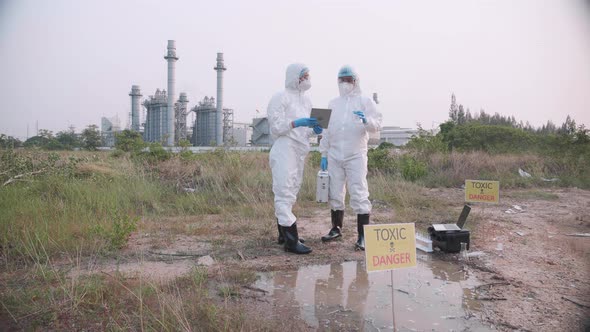 Two Scientists in protective suits and masks took a sample of water for analysis. alt