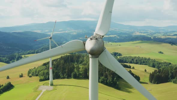 Zoom Out of Camera From a Propeller of the Windmill in the Field with Mountains on the Background alt