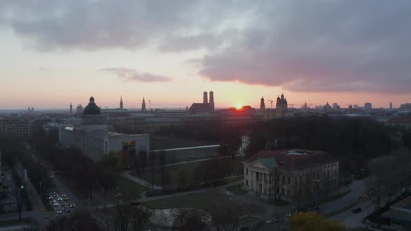 Slow Forward Aerial Above Munich Cityscape in Germany with Setting Sun in Red Golden Light and View alt