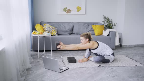 Young Woman with Long Fair Hair in Ponytail Practices Yoga