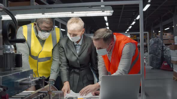 Team of Engineers in Safety Mask Discussing Blueprint at Workplace at Manufacturing Plant alt