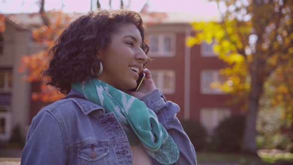 College student on campus in fall talking on cell phone